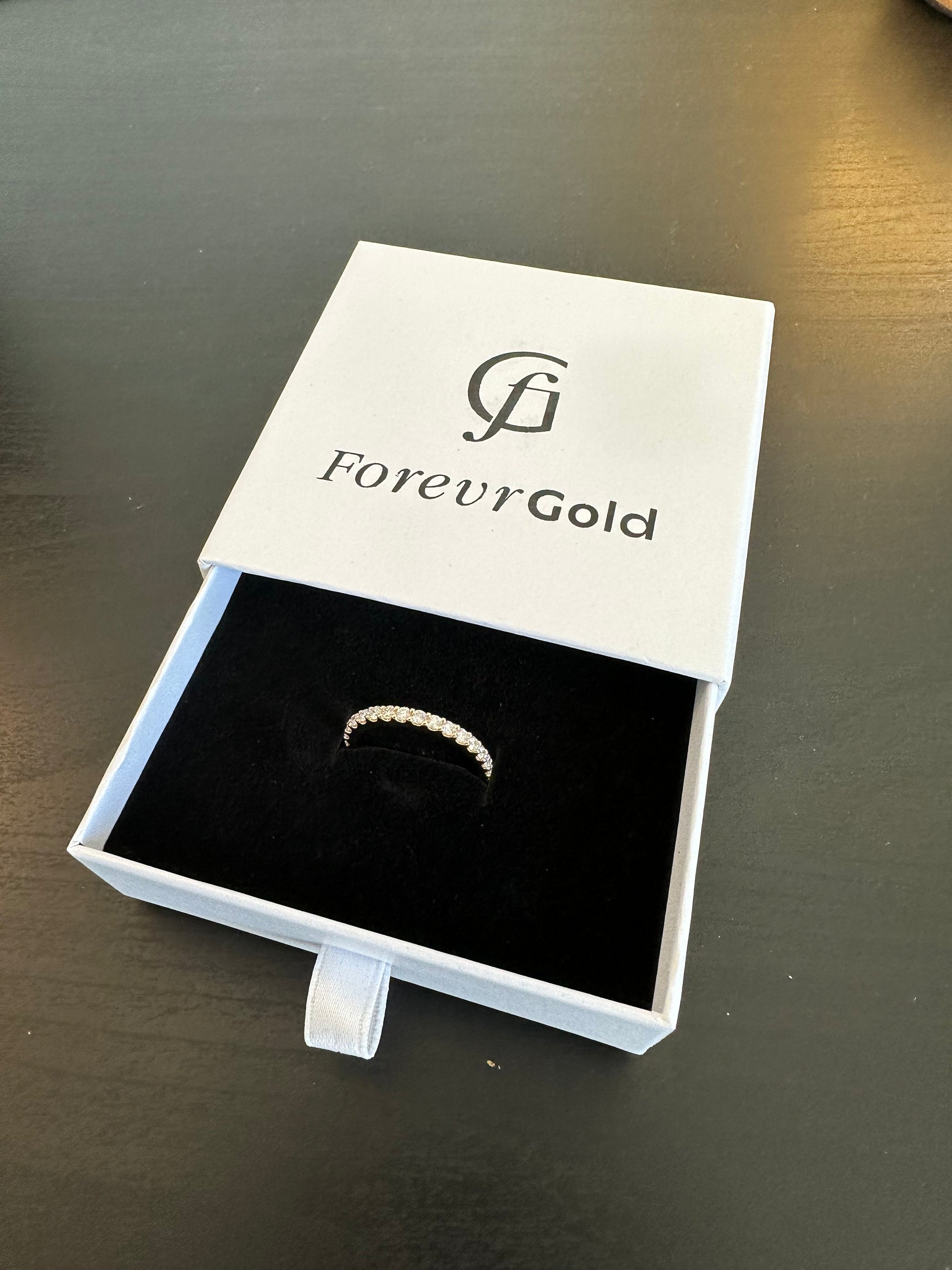 Three Quarter Pave Round Band in a 'Forever Gold' box on a dark surface